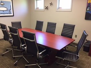 A conference room with a long red table and black chairs