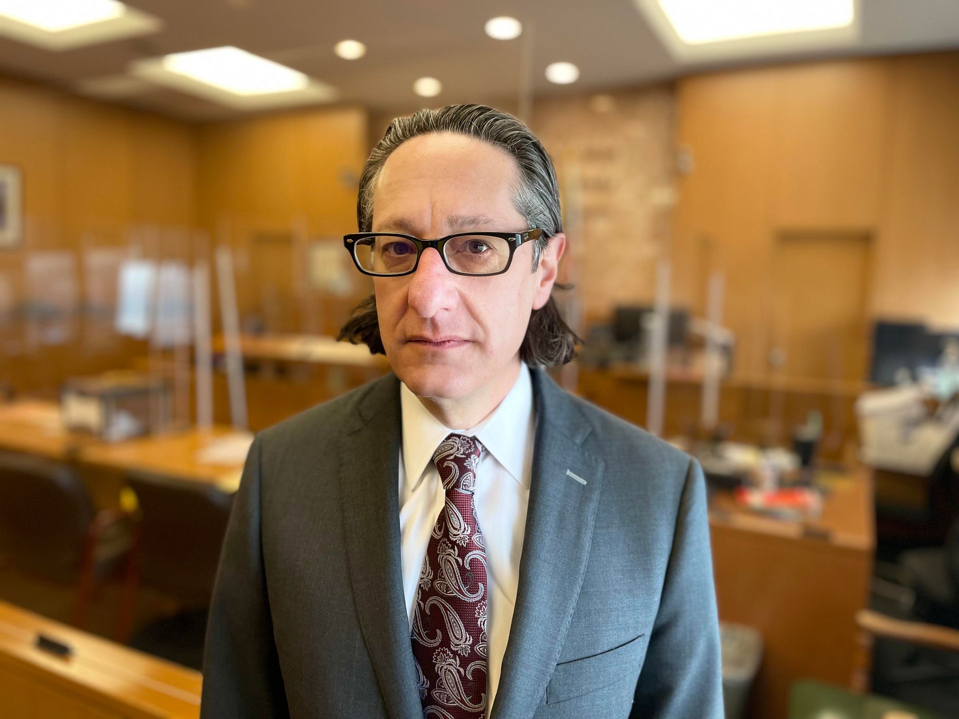 A man in a suit and tie is standing in a courtroom.