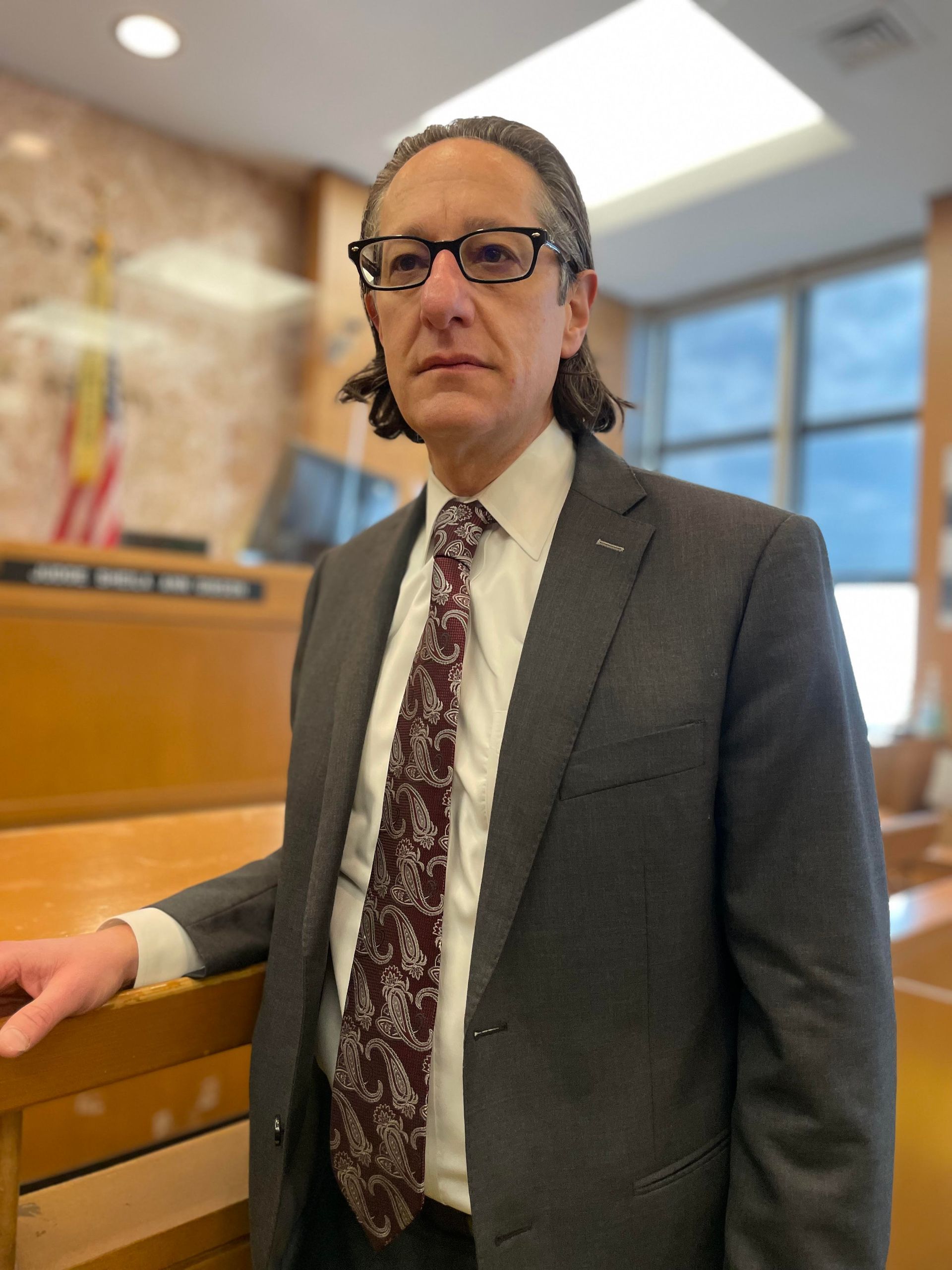 A man in a suit and tie is standing in a courtroom.