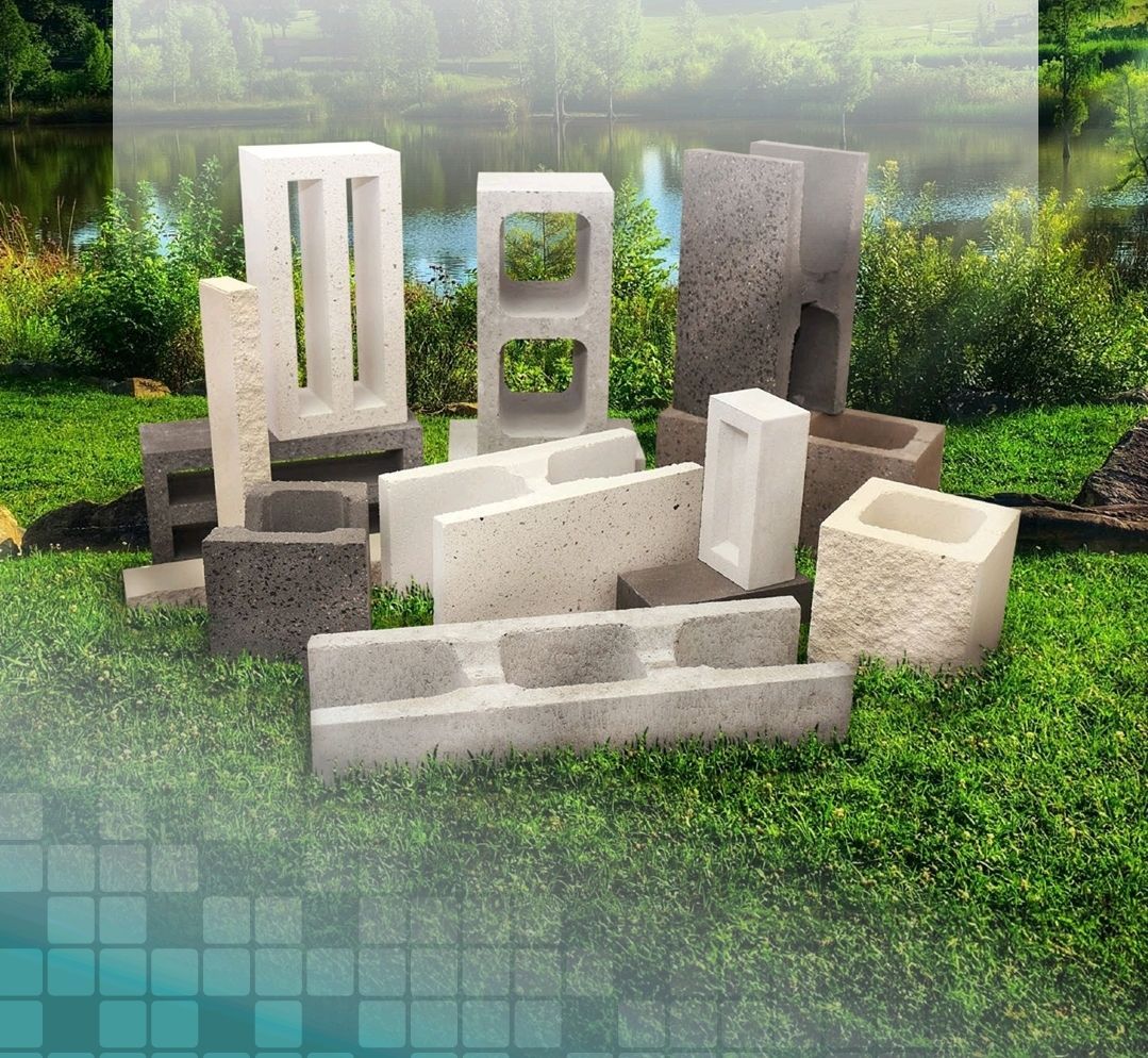 Concrete blocks of various shapes and sizes on green grass, with a blurred background of water and trees - Palms Landscape Supplies in Forster, NSW