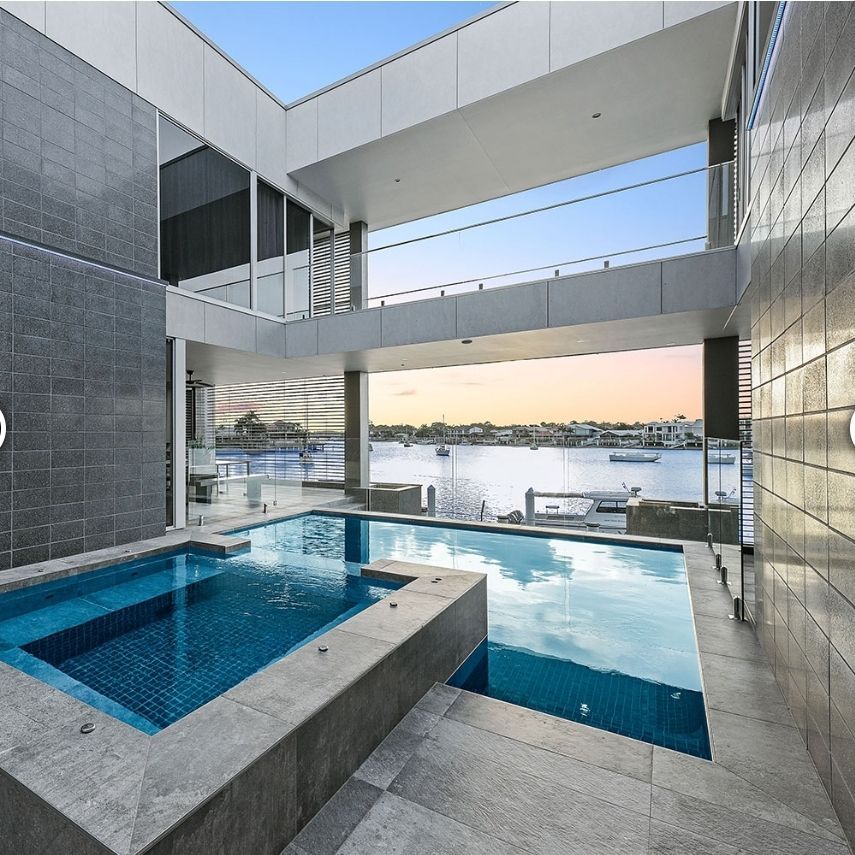 Pool and jacuzzi overlooking a waterway from a modern, multi-level building - Palms Landscape Supplies in Forster, NSW