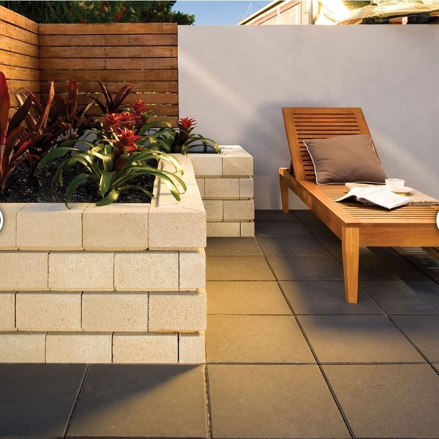 Outdoor patio with a chaise lounge, brick planters with plants, and a wood fence - Palms Landscape Supplies in Forster, NSW