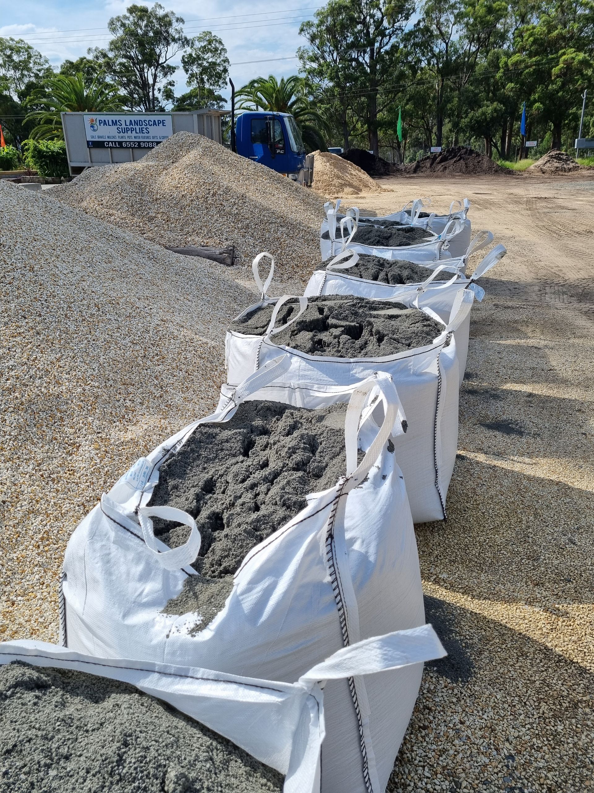 Five white bags filled with grey gravel on a gravel lot - Palms Landscape Supplies in Forster, NSW