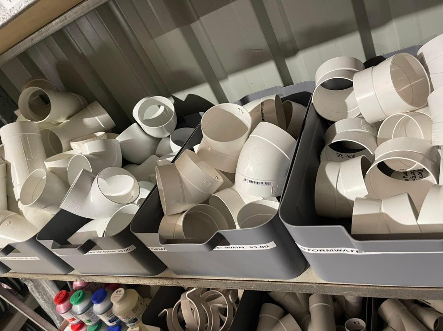 White PVC pipe fittings overflowing grey storage bins - Palms Landscape Supplies in Forster, NSW