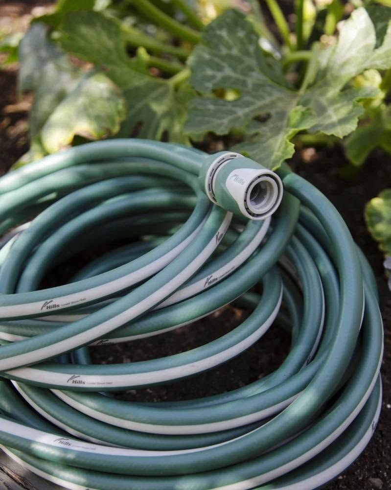Coiled green and white garden hose with connector, in a garden setting - Palms Landscape Supplies in Forster, NSW