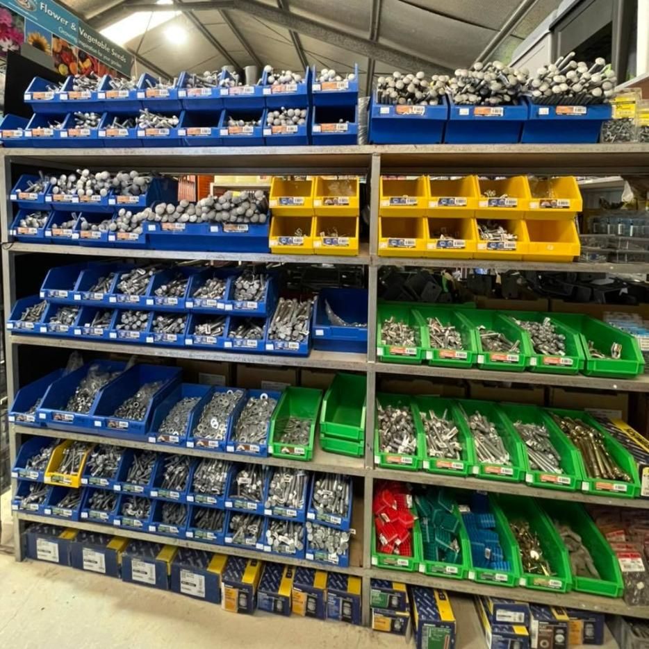 Shelving unit filled with bins of hardware, including bolts and screws in blue, yellow, and green containers - Palms Landscape Supplies in Forster, NSW