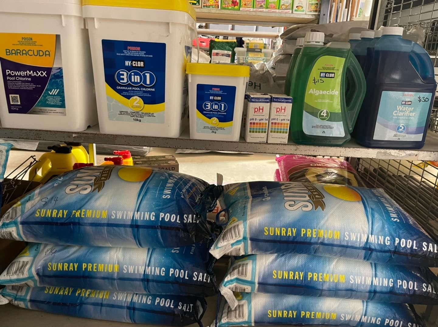 Shelves stocked with pool supplies: salt bags, chemicals in buckets and jugs - Palms Landscape Supplies in Forster, NSW