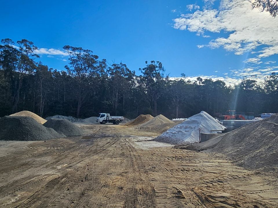 Piles of gravel and sand at a construction site, truck in the middle - Palms Landscape Supplies in Forster, NSW