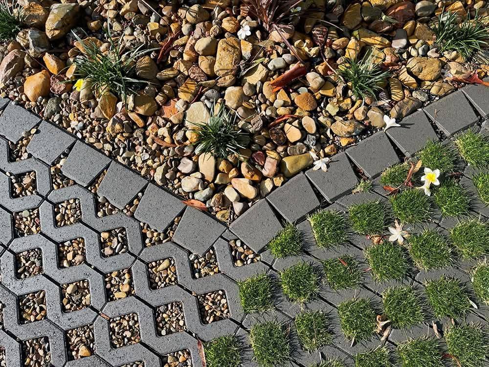 Section of a walkway with alternating gravel, grass, and patterned gray pavers - Palms Landscape Supplies in Forster, NSW