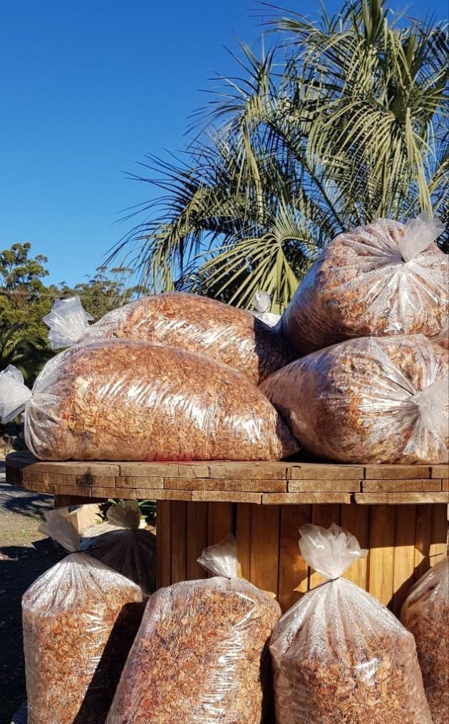 Bags of brown mulch piled on a wooden structure outdoors - Palms Landscape Supplies in Forster, NSW