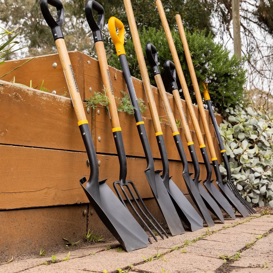 Garden tools, shovels and forks, lined up against a wooden raised garden bed - Palms Landscape Supplies in Forster, NSW