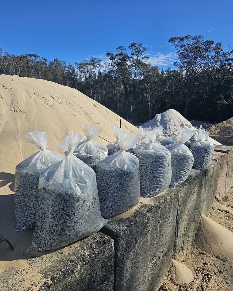 Bags filled with dark-coloured gravel sit atop a concrete ledge - Palms Landscape Supplies in Forster, NSW