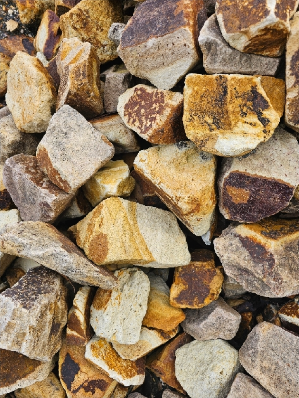 Pile of tan, brown, and rust-coloured rocks, likely gravel or decorative stones - Palms Landscape Supplies in Forster, NSW
