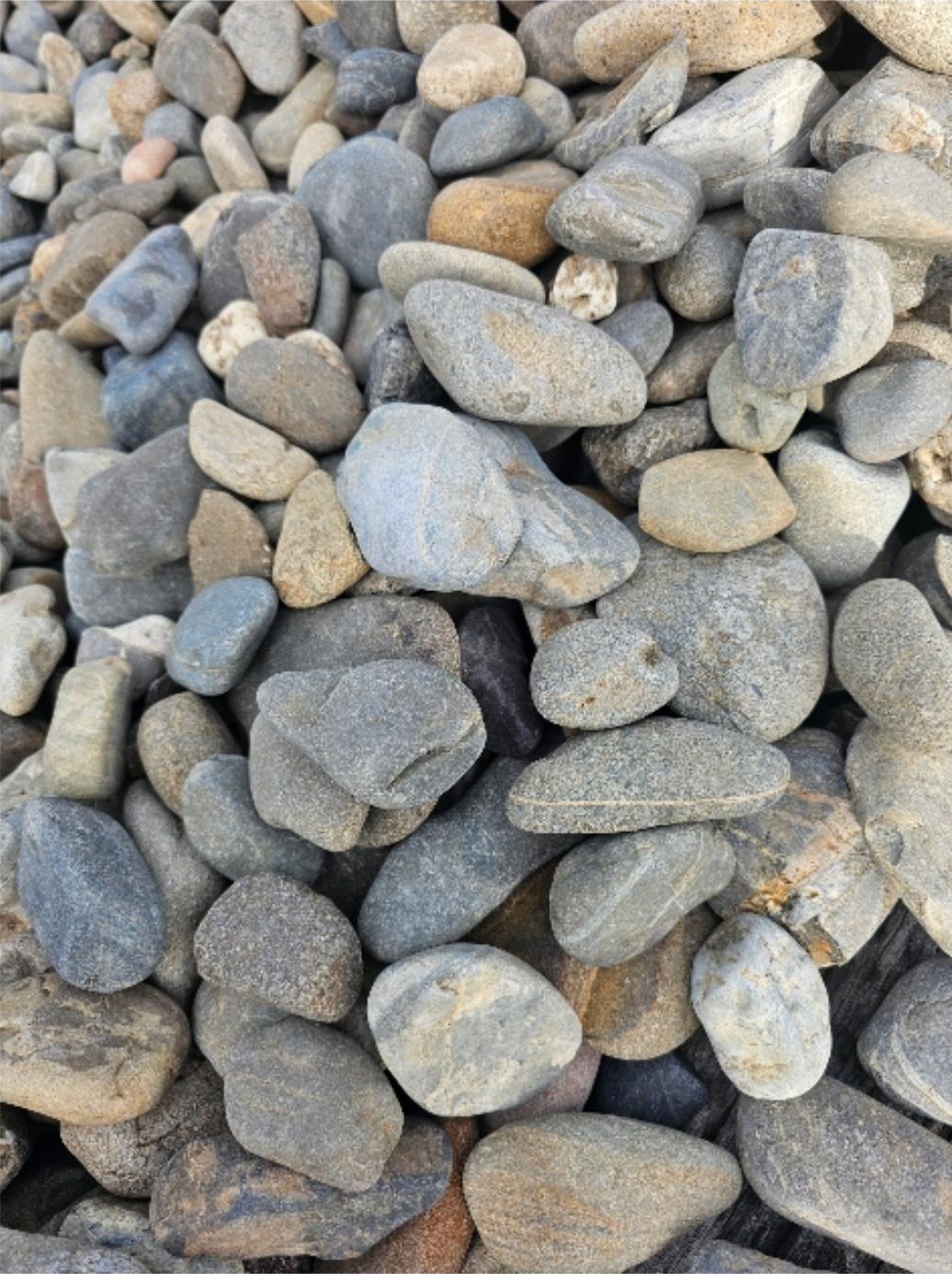 Pile of rounded river rocks, various shades of grey, tan, and brown - Palms Landscape Supplies in Forster, NSW