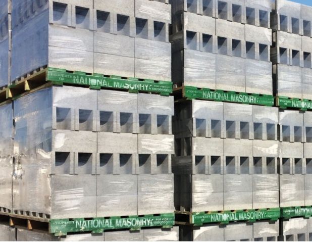 Stacks of grey concrete blocks wrapped in plastic, stacked on green pallets - Palms Landscape Supplies in Forster, NSW