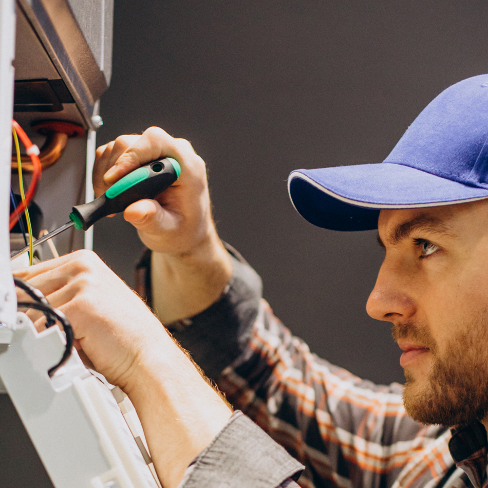Hombre con gorra azul usando un destornillador en cables.