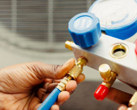 Persona que conecta una manguera azul a un colector de medición, probablemente para reparar el aire acondicionado.