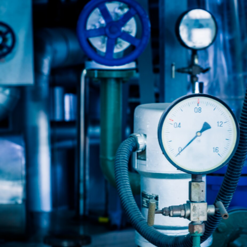Manómetro en maquinaria industrial, tonos azules.