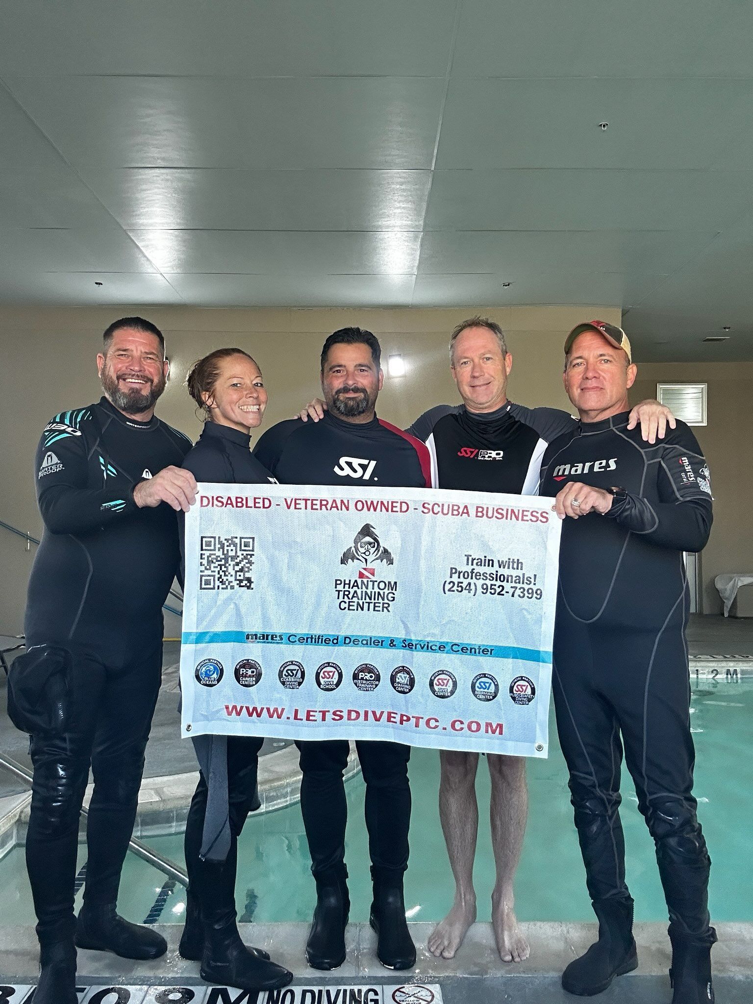 Man in scuba gear, snorkel, and mask in pool, adjusting equipment.