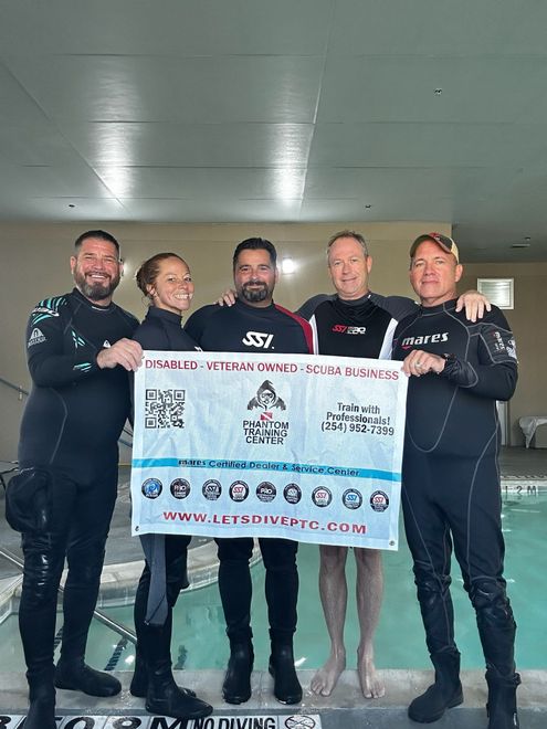 Man in scuba gear, snorkel, and mask in pool, adjusting equipment.