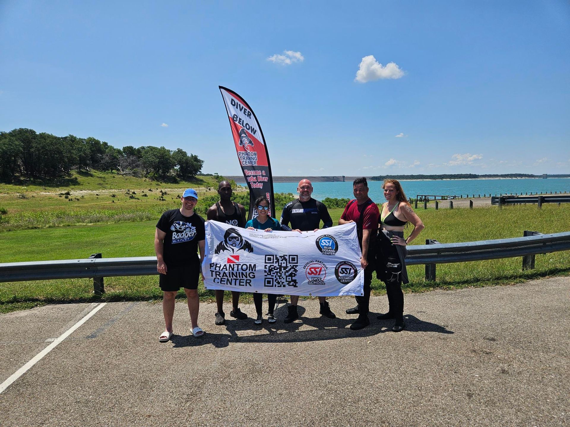 Group of people in blue shirts posing outdoors, sunny day.