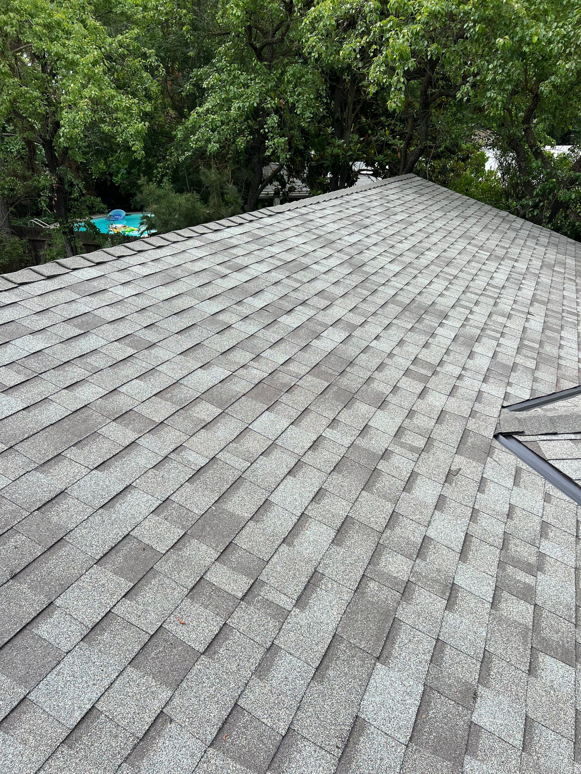 A roofer installing shingles on a residential roof in clovis under a clear blue sky