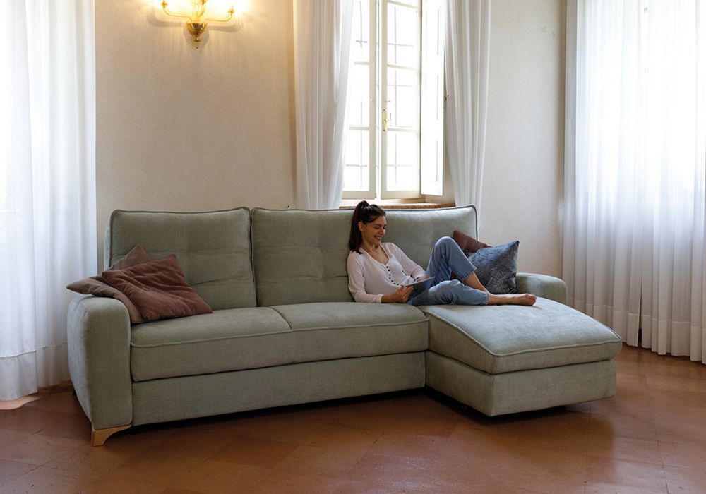 Un divano verde è posizionato in un soggiorno accanto a un tavolo.