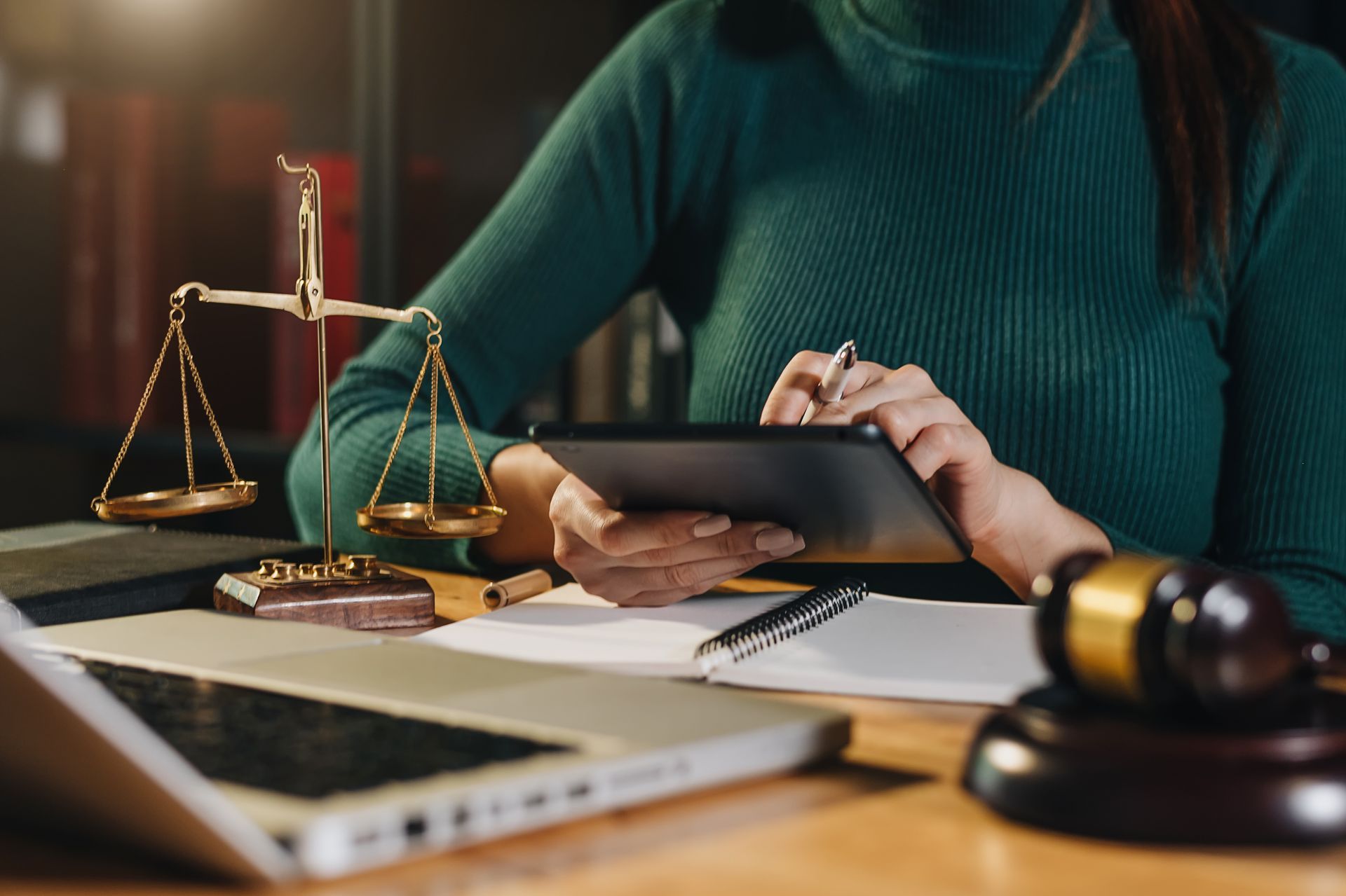 A lawyer working with a digital tablet. A laptop, gavel & scales of justice are on the table A lawyer working with a digital tablet. A laptop, gavel & scales of justice are on the table