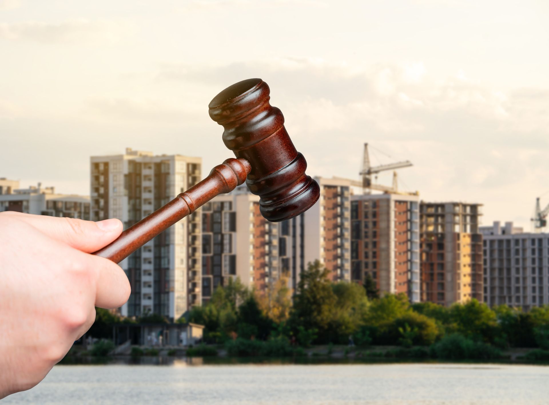 A hand holds a wooden gavel in front of blurry high-rise buildings, representing probate law.