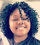A young woman with curly hair is smiling for the camera.