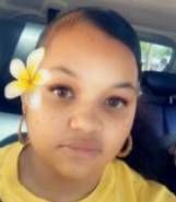 A young girl with a flower in her hair is sitting in a car.