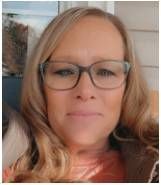 A woman wearing glasses is smiling for the camera.