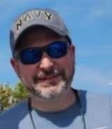 A man with a beard is wearing a hat and sunglasses.