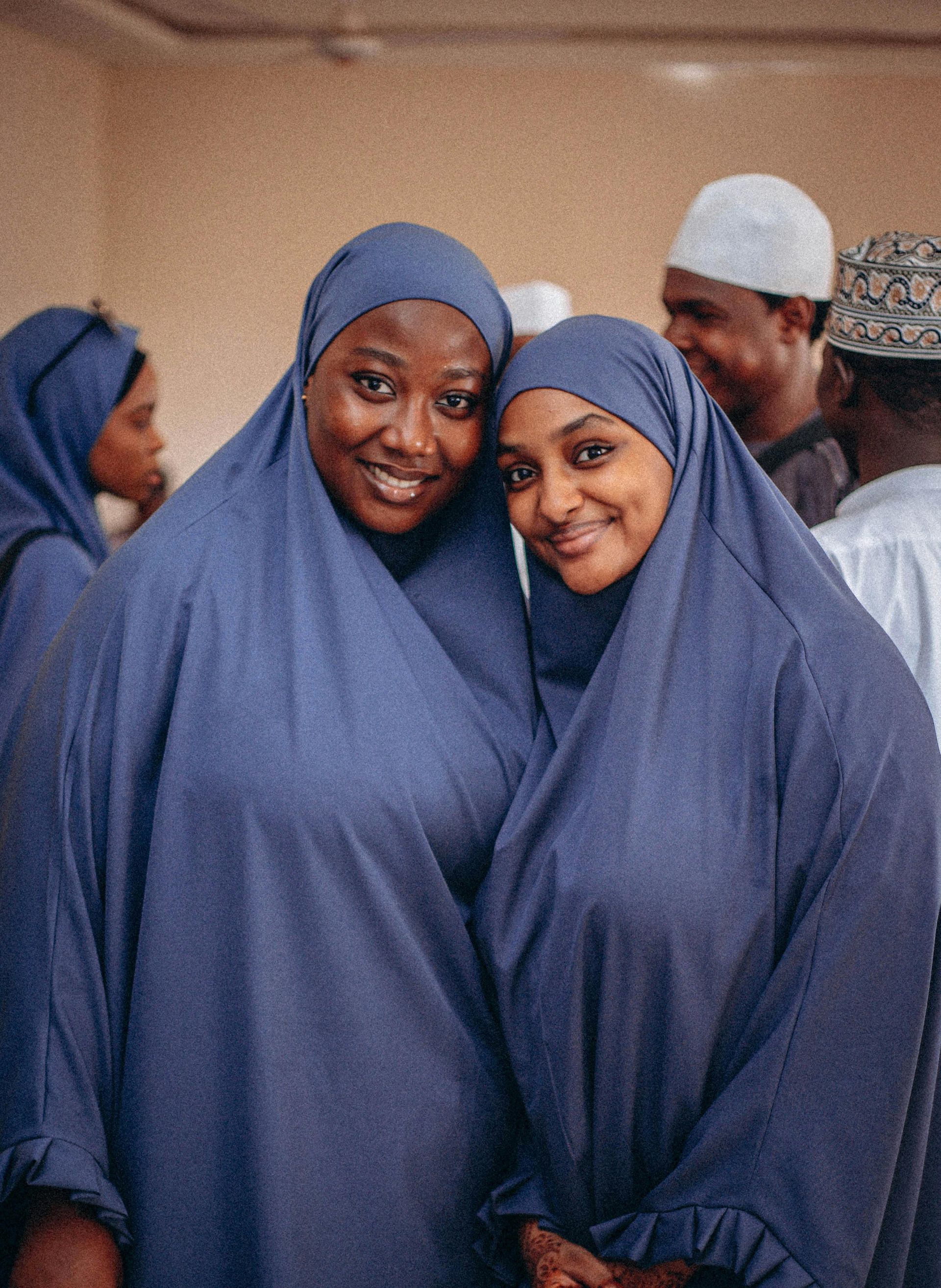 Two women wearing blue hijabs are posing for a picture together.