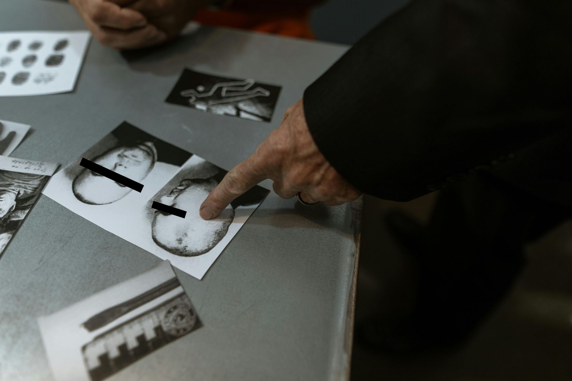 A person is pointing at a picture of a man 's face on a table.