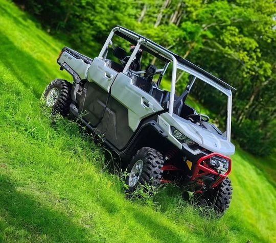 A white atv is driving down a grassy hill