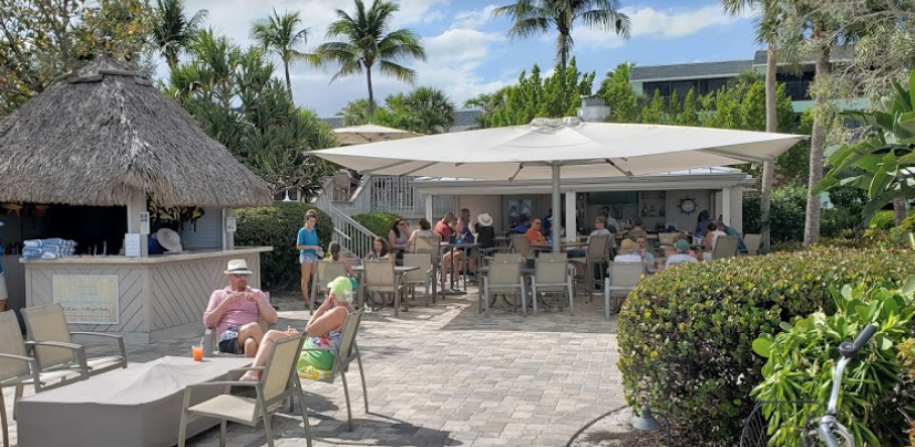 A group of people are sitting at tables under umbrellas at a restaurant.