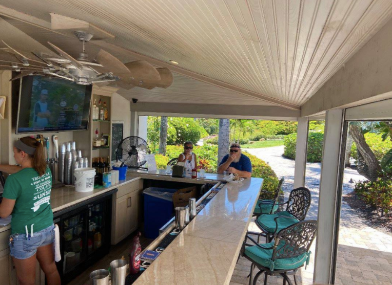 A woman in a green shirt is standing at a bar.