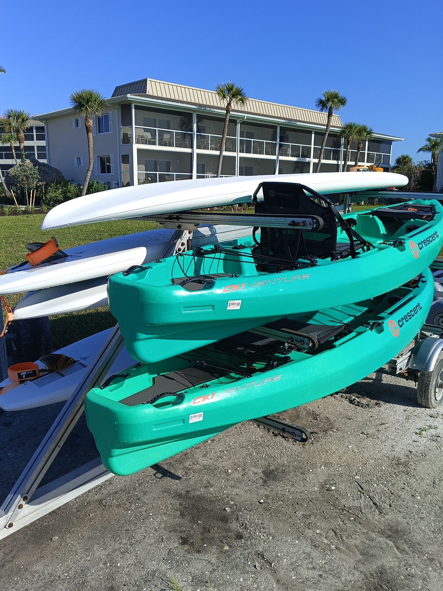 Three green kayaks are stacked on top of each other on a trailer.