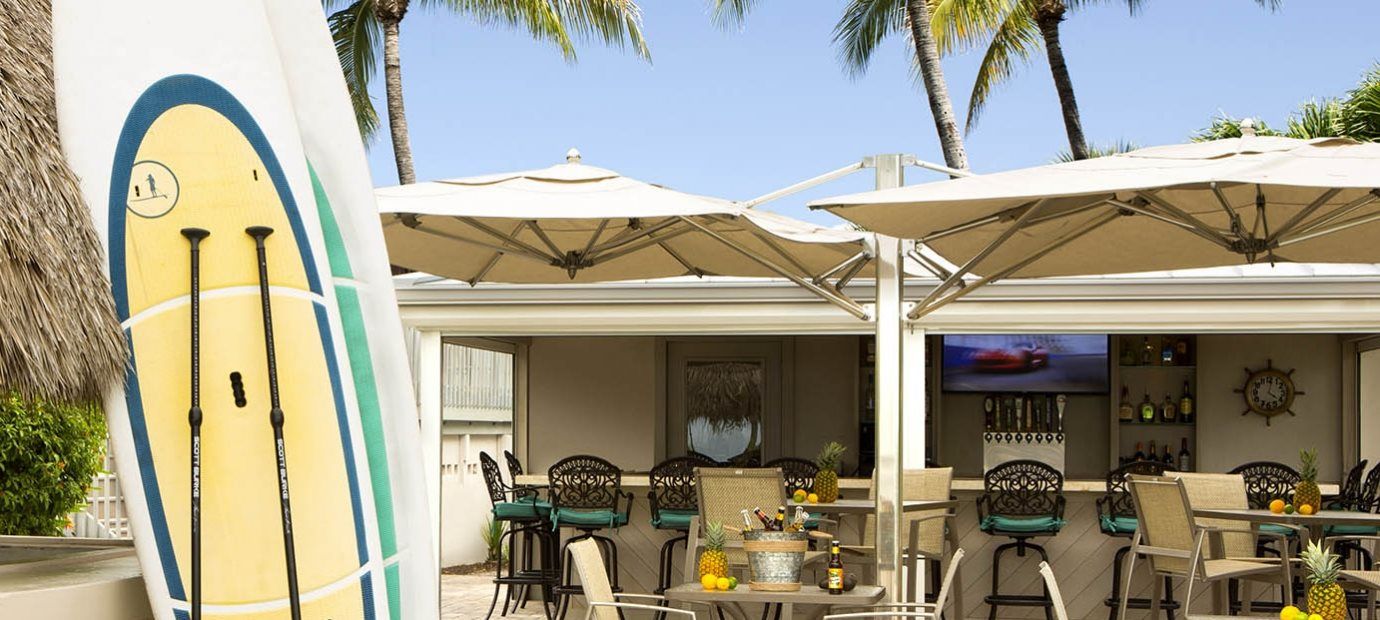A surfboard is sitting in front of a restaurant with tables and chairs.