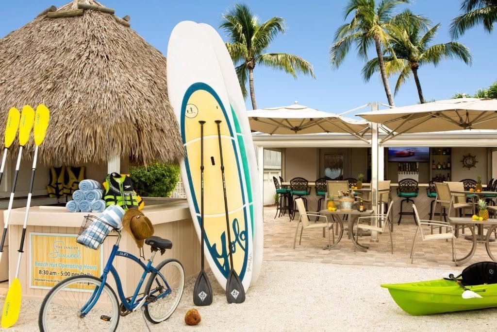 A bicycle is parked on the beach next to a surfboard and kayak.