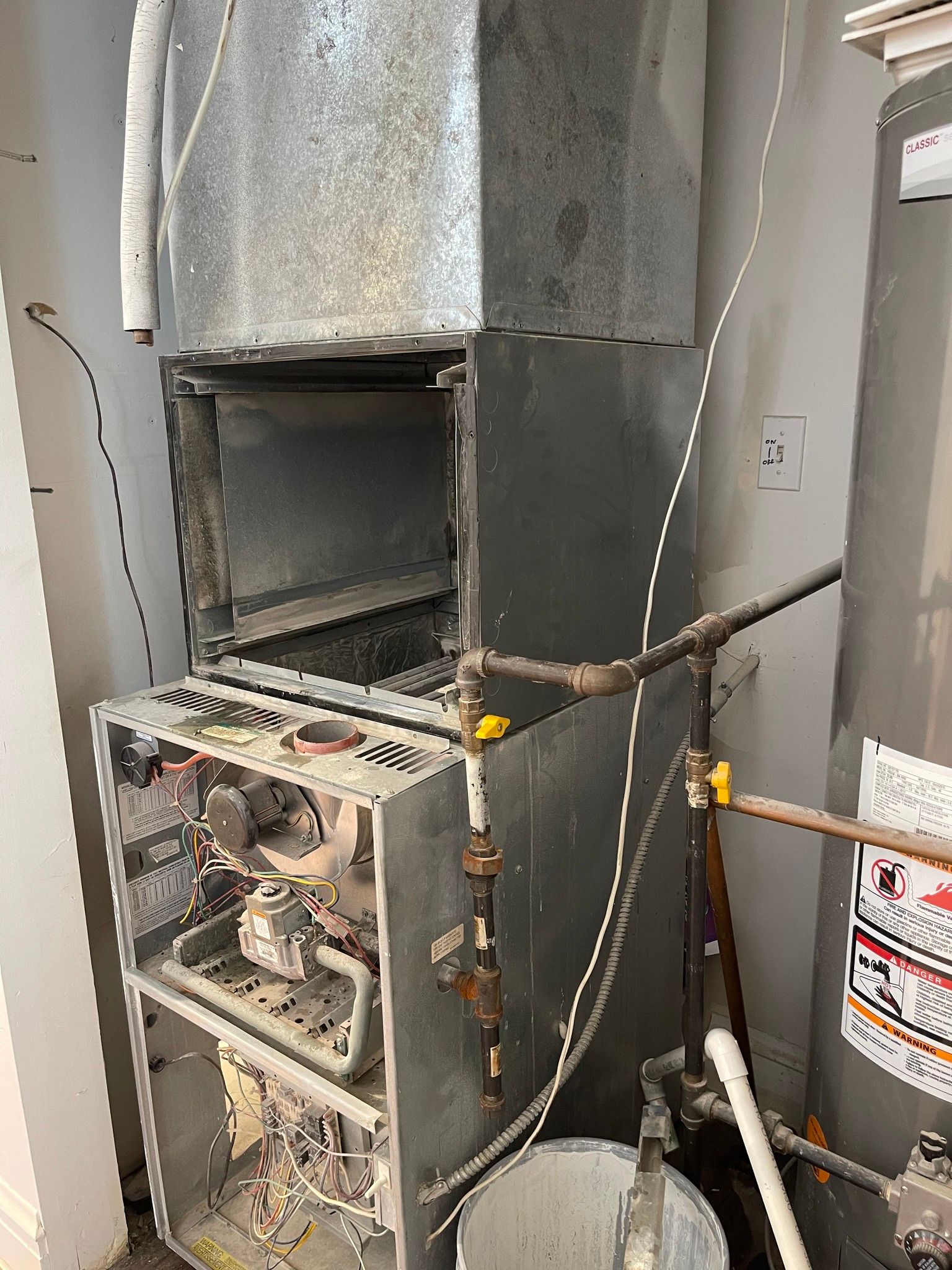 Furnace and ductwork in a utility room. Open furnace shows internal components and wires.