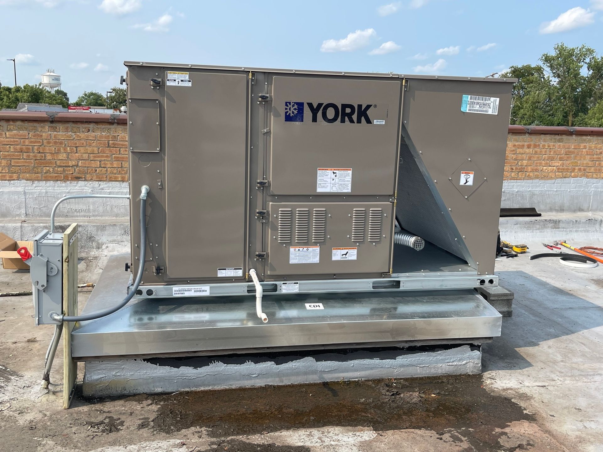 York rooftop HVAC unit on a flat roof. Beige and silver. Sunny day.