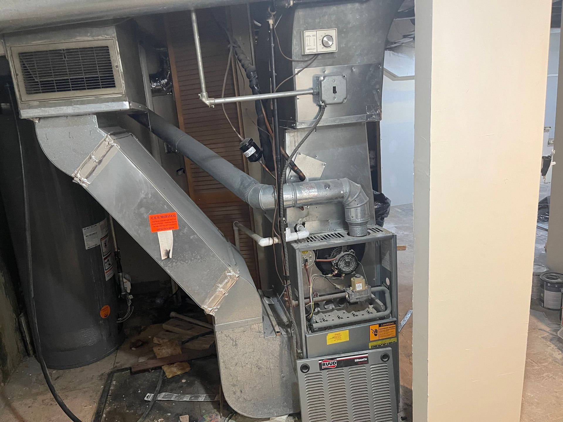 Furnace and ductwork in a basement, various metal components, wires, and a vent.