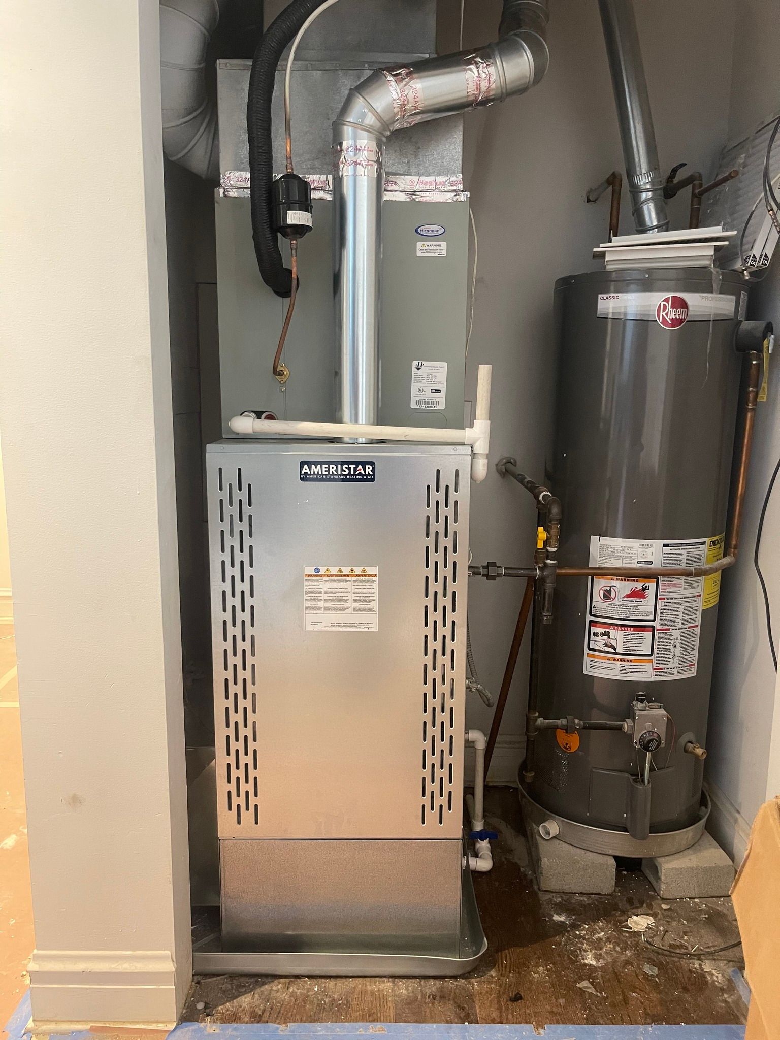 Furnace and water heater in a utility closet. Silver appliances against gray walls.