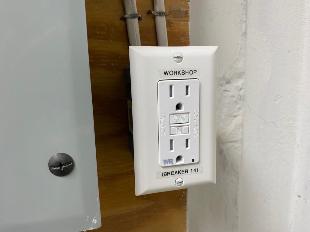 An electrician is working on an electrical box with a screwdriver.