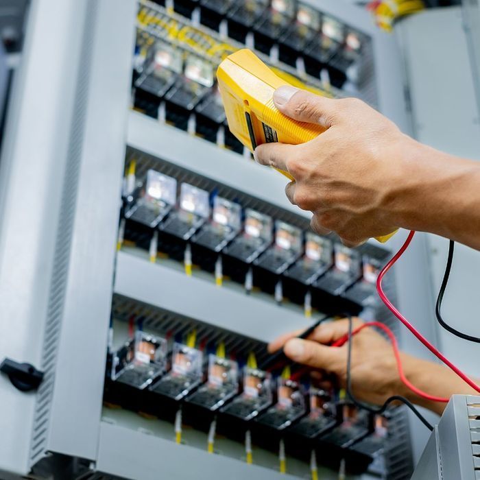 A man wearing gloves is working on an electrical box.