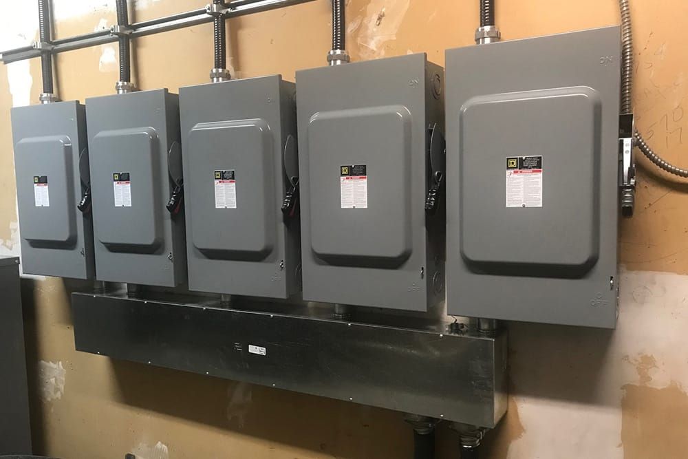An electrician is working on an electrical box with a screwdriver.