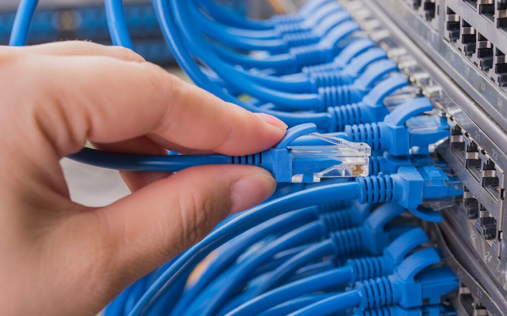 An electrician is working on an electrical box with a screwdriver.