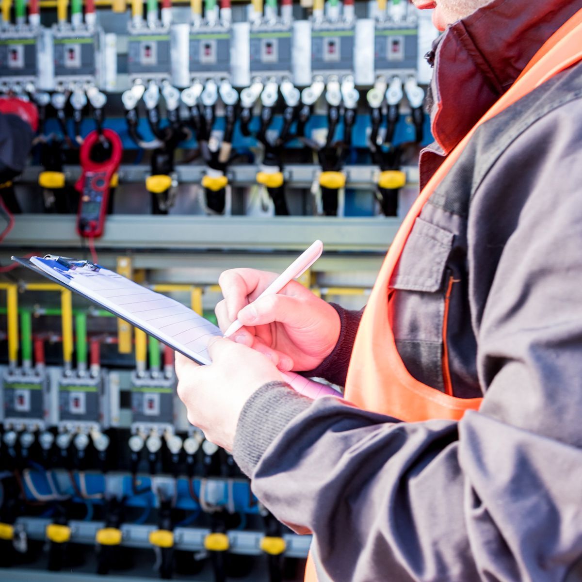 An electrician is working on an electrical box with a screwdriver.